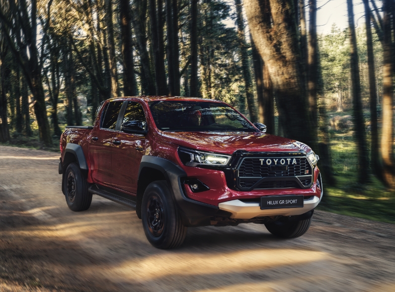 Czerwona Toyota Hilux GR SPORT jedzie leśną drogą